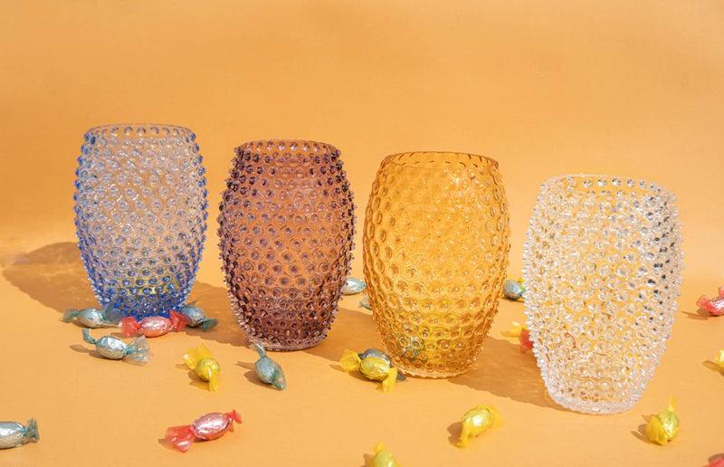 Underlay Violet Egg Hobnail Vase on a yellow floor surrounded by candies