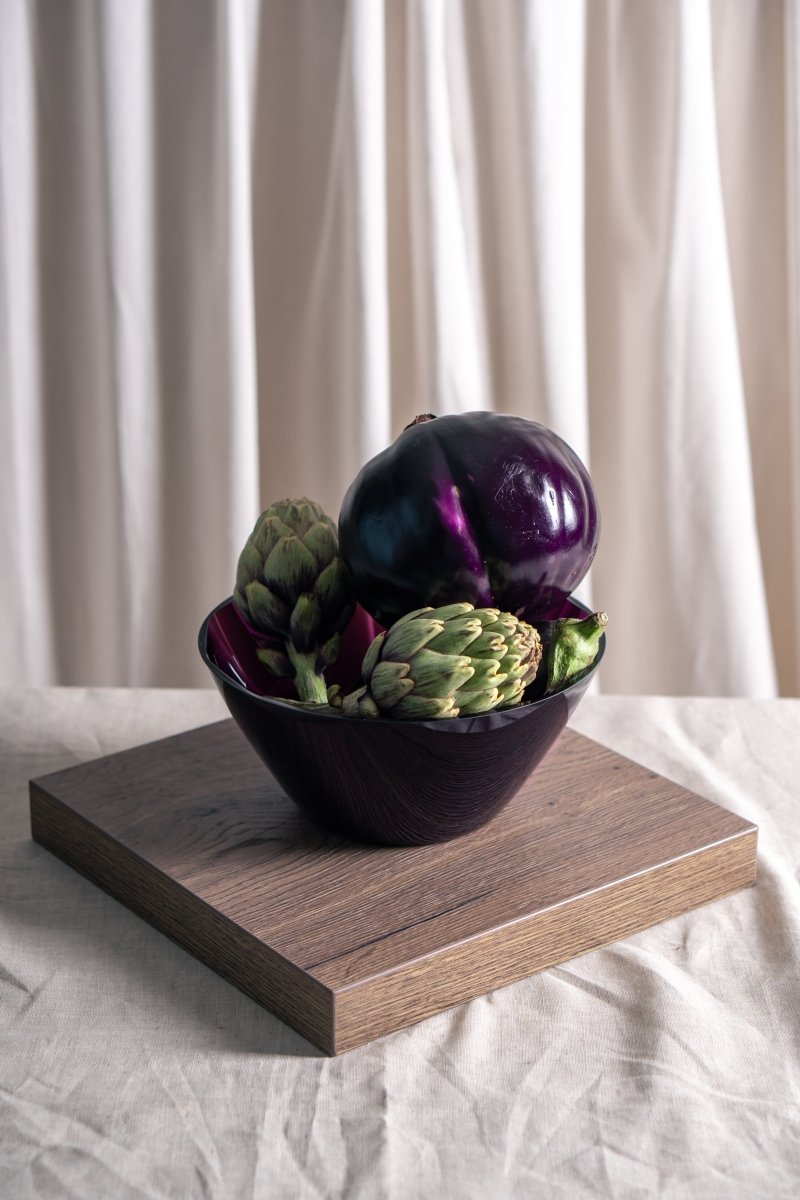 Violet Marika Bowl on a rectangular wooden room, a white background and colorful vegetables 