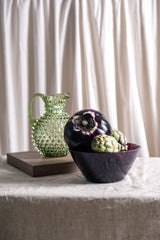 Violet Marika Bowl on a grey fabric and white background, with coloured vegetables