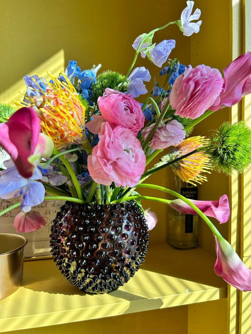 Violet Hobnail Vase on a yellow cabinet with colorful flowers